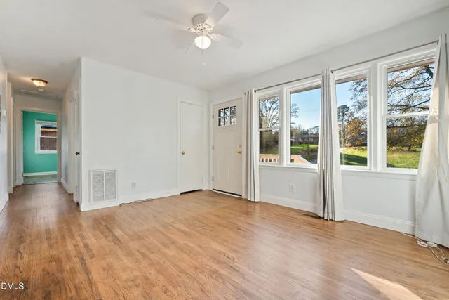 a view of an empty room with wooden floor and a window