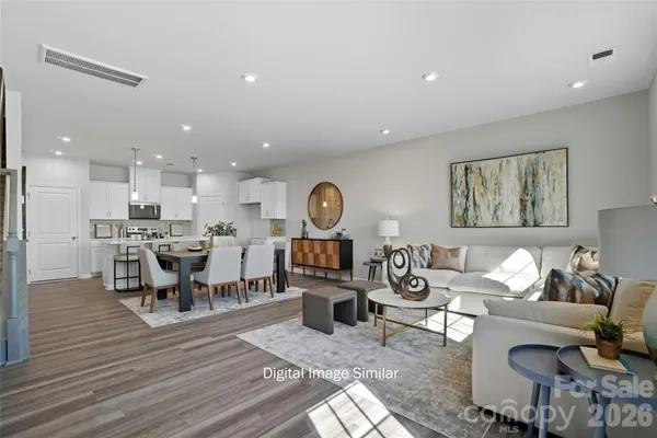 a living room with furniture kitchen view and a wooden floor