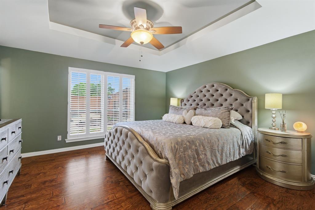2307 Castle Rock Road Carrollton, TX 75007 - Photo 19 of 34 This bedroom features hardwood floors, a tray ceiling, and a ceiling fan