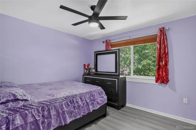a view of an empty room with window ceiling fan and wooden floor