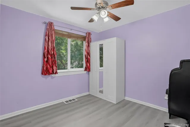 a view of a livingroom with a ceiling fan & windows