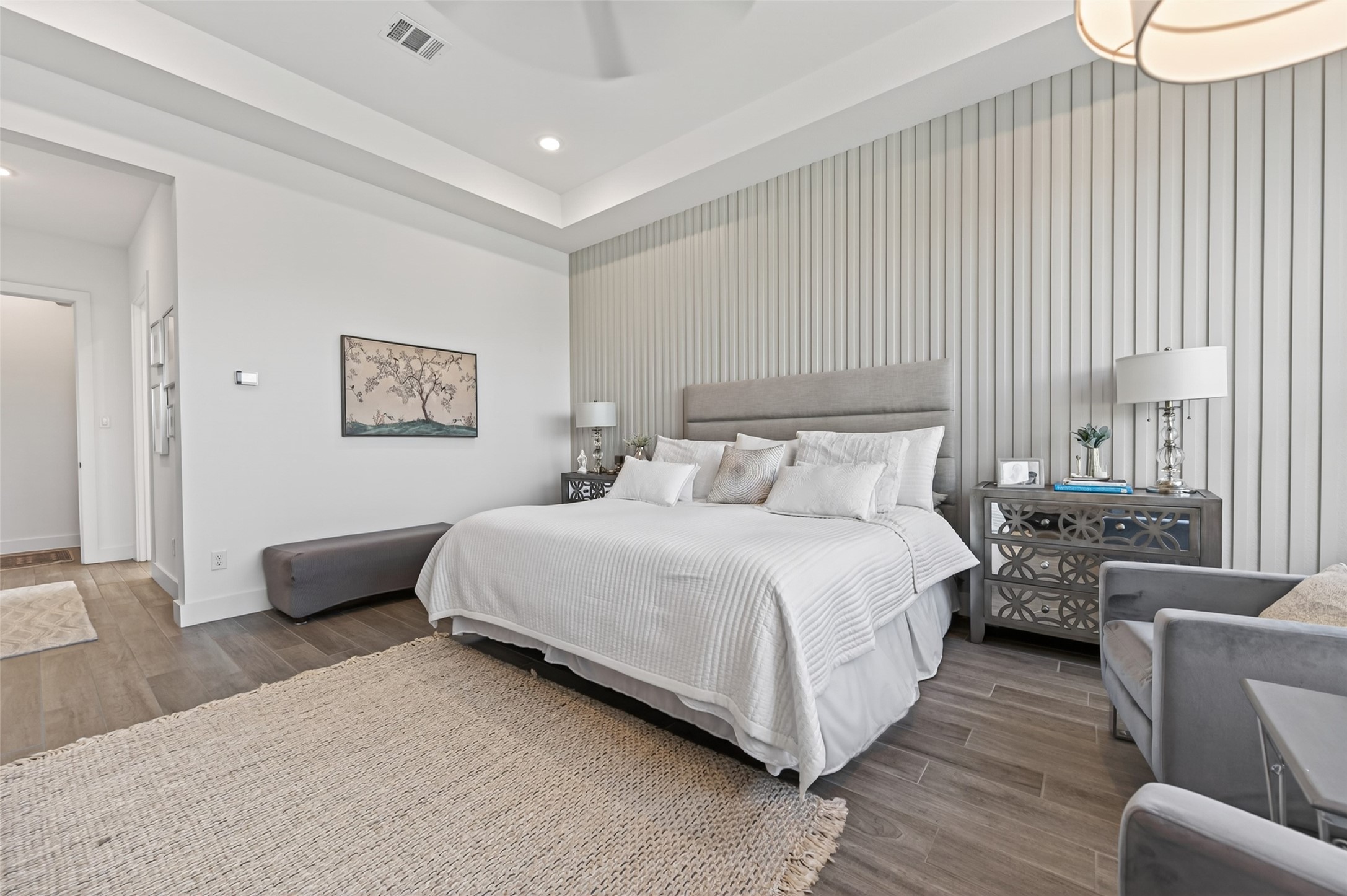 29612 Fulshear Lake Trace Fulshear, TX 77406 - Photo 34 of 48 This MASTER bedroom features a spacious layout with a modern design. It includes an elegant wall paneling. The room has a neutral color palette, wooden flooring, and ample natural light, creating a cozy and inviting atmosphere.