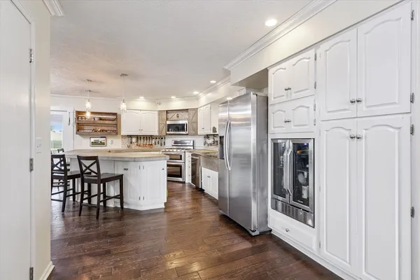 a kitchen with stainless steel appliances granite countertop a stove top oven a sink dishwasher a dining table and chairs with wooden floor