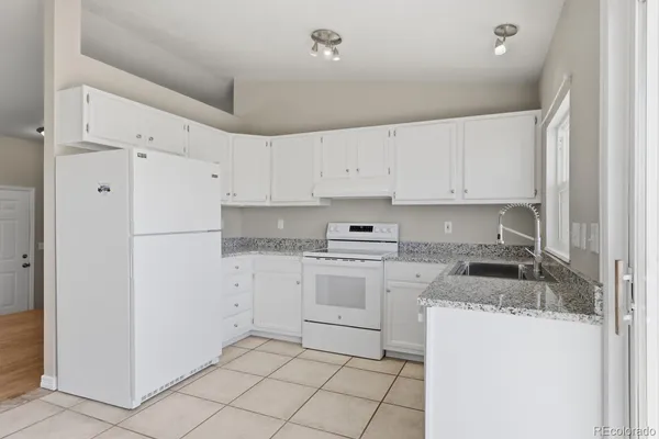 a kitchen with granite countertop white cabinets and refrigerator
