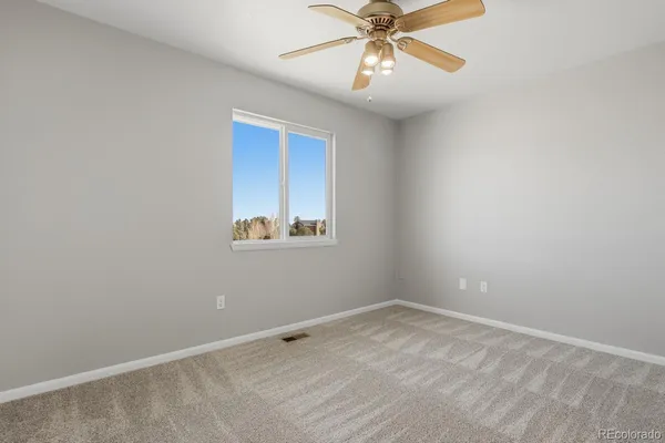 an empty room with a window and a fan