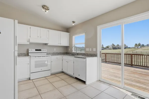 a kitchen with granite countertop white cabinets and white appliances