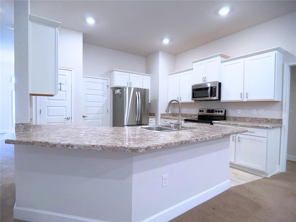4549 Southeast 25th Loop Ocala, FL 34480 - Photo 8 of 25 a kitchen with stainless steel appliances granite countertop a sink a stove a refrigerator a window and white cabinets