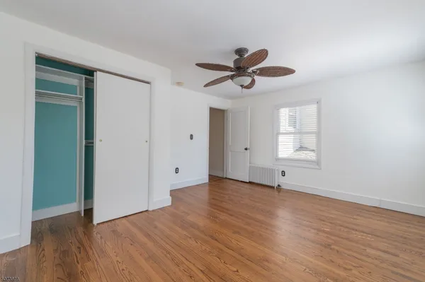 an empty room with wooden floor chandelier fan and windows