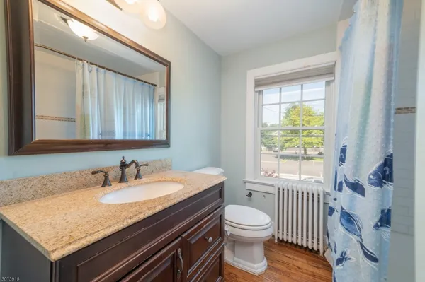 a bathroom with a granite countertop sink a toilet and a window