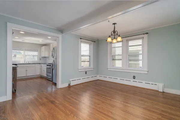 a view of an empty room with window and wooden floor