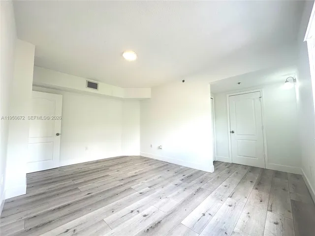 a view of room with wooden floor and white walls
