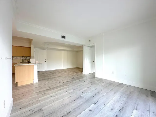 a view of kitchen and empty room with wooden floor