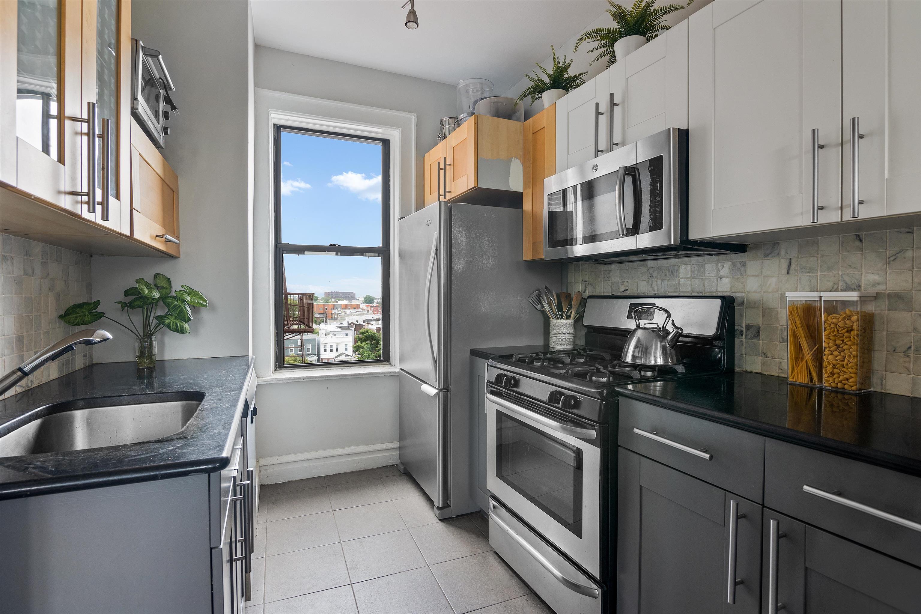 277 Harrison Avenue, Unit E6 Jersey City, NJ 07304 - Photo 4 of 14 a kitchen with stainless steel appliances granite countertop white cabinets and window