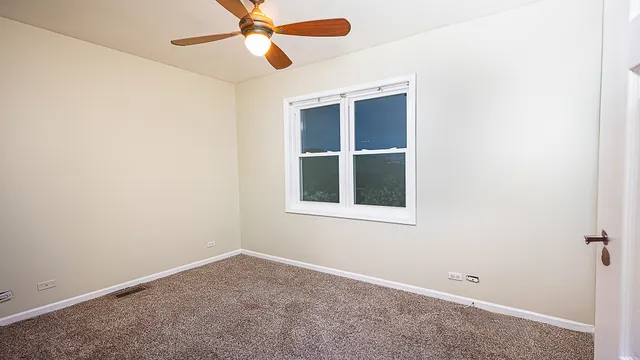 an empty room with a window and a fan