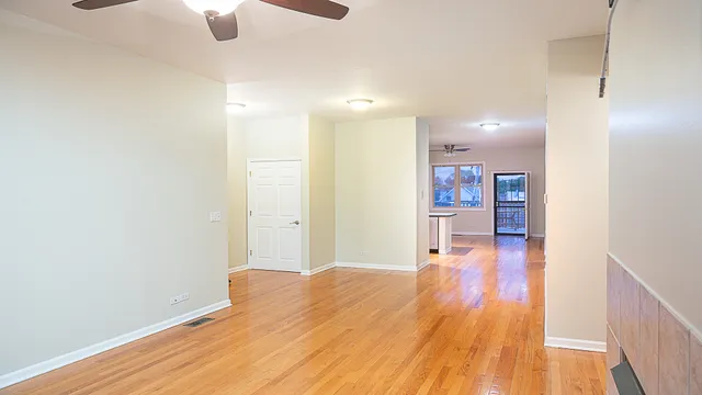 a view of a room with wooden floor and a ceiling fan