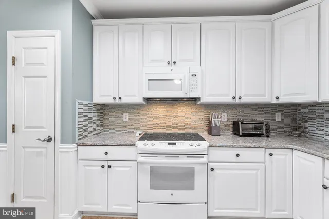 a kitchen with white cabinets and white appliances