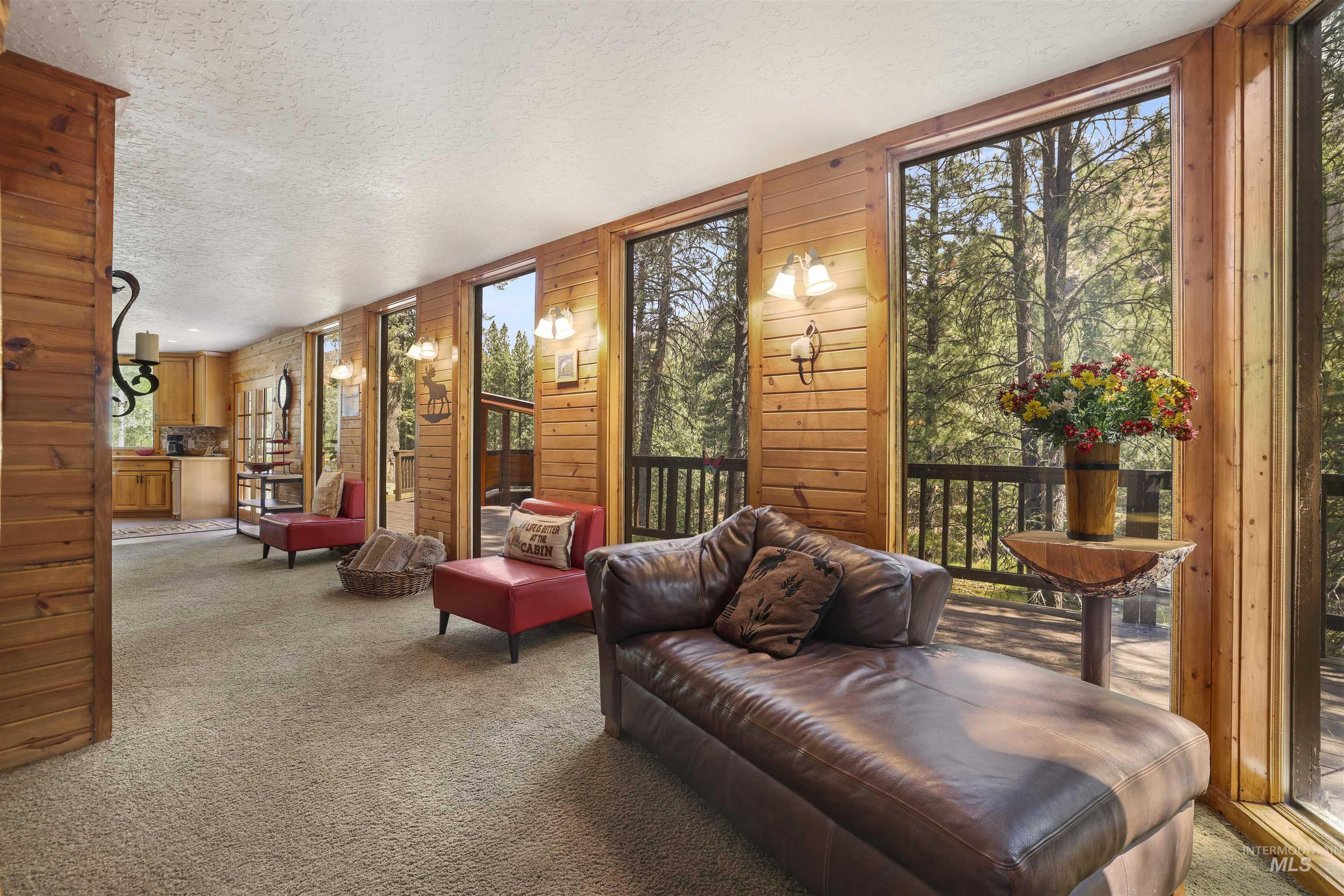 224 Dakota Road Mountain Home, ID 83647 - Photo 6 of 50 Floor-to-ceiling windows line the wood-paneled walls, framing the outdoor tree canopy