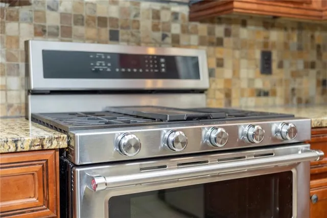 a living room with stainless steel appliances granite countertop a refrigerator and a stove top oven