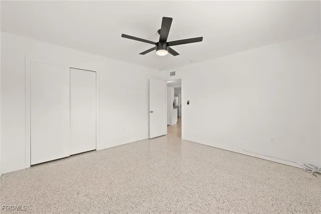 an empty room with a ceiling fan and a window