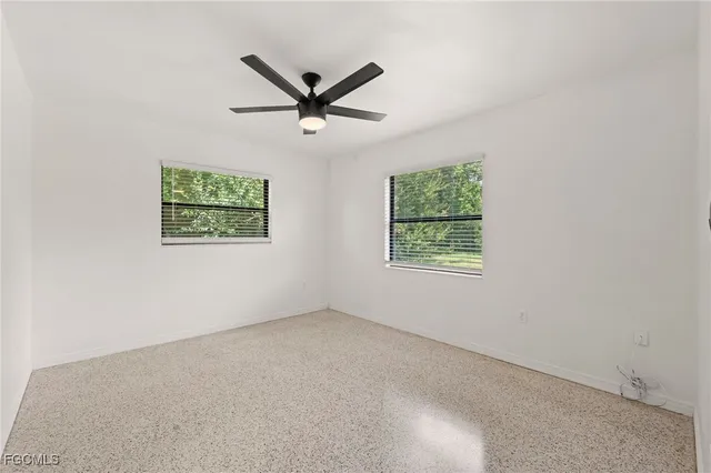 an empty room with windows and fan