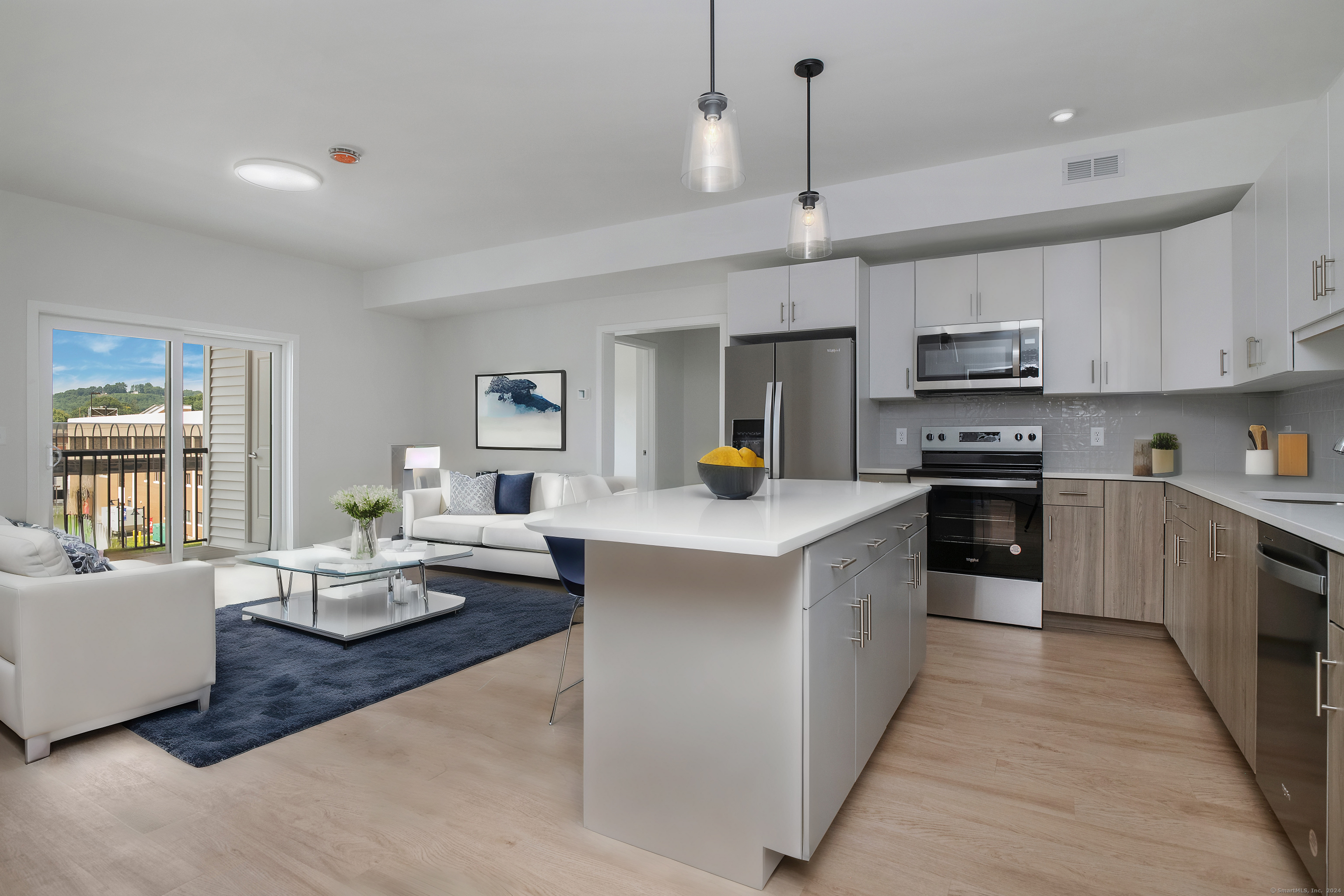 100 North Main Street, Unit 103 Bristol, CT 06010 - Photo 4 of 10 a large kitchen with stainless steel appliances kitchen island granite countertop a sink dishwasher a stove a dining table and chairs with wooden floor