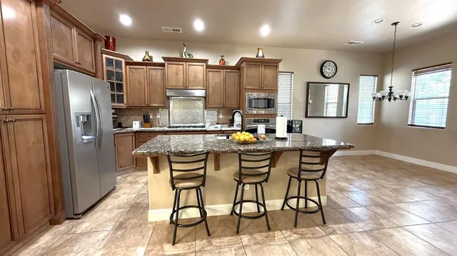 a kitchen with stainless steel appliances kitchen island granite countertop a refrigerator and microwave