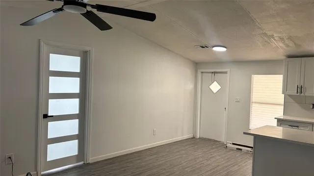 a view of empty room with wooden floor and fan