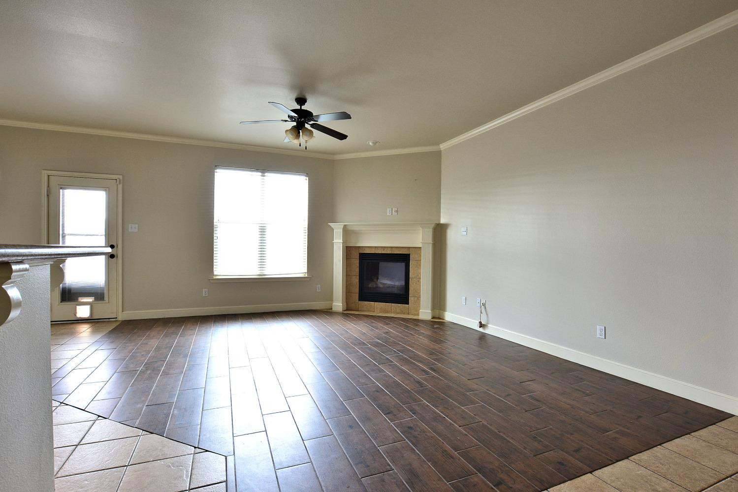 2623 112th Street Lubbock, TX 79423 - Photo 4 of 16 an empty room with wooden floor fireplace and windows