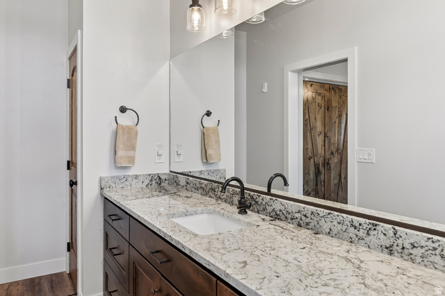 3311 West Allard Summit, UT 84772 - Photo 53 of 97 Bathroom vanity featuring a light-toned stone countertop, integrated rectangular sink, dark bronze faucet, and a large wall-mounted mirror