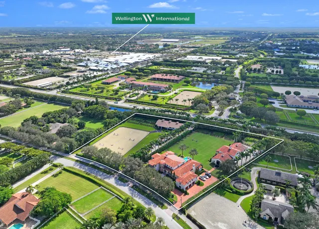 an aerial view of a tennis ground and a cars park side of the road
