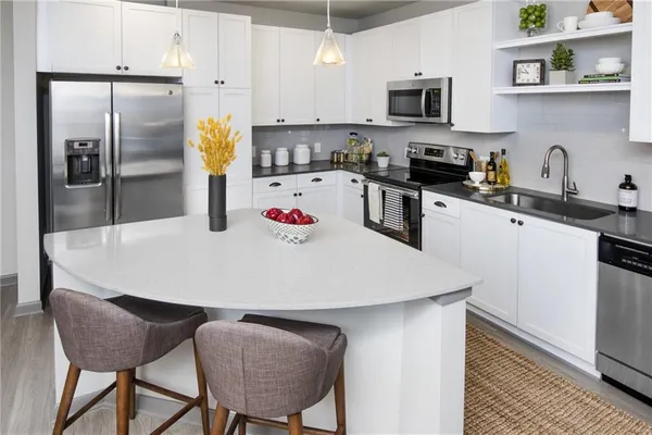 a kitchen with stainless steel appliances granite countertop a refrigerator a stove and a sink with wooden floor