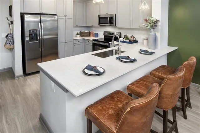 a kitchen with stainless steel appliances granite countertop a table chairs and a refrigerator