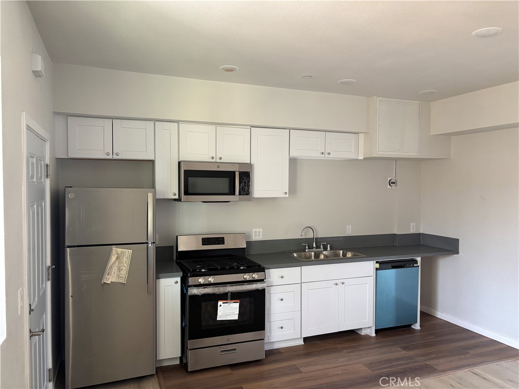 2683 San Marino Street Los Angeles, CA 90006 - Photo 7 of 10 a kitchen with stainless steel appliances granite countertop a refrigerator stove a sink and white cabinets