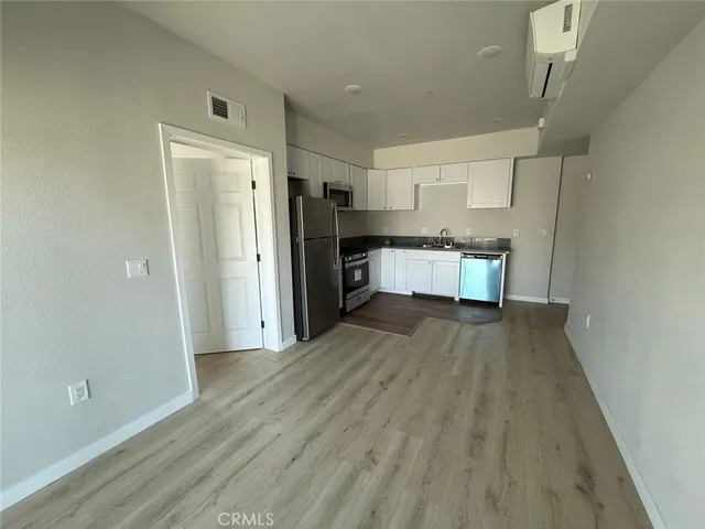 a large kitchen with a wooden floor and a refrigerator