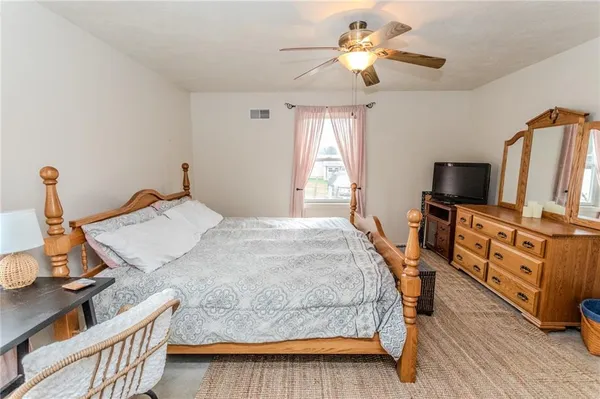 a bedroom with a bed and a flat tv screen on dresser