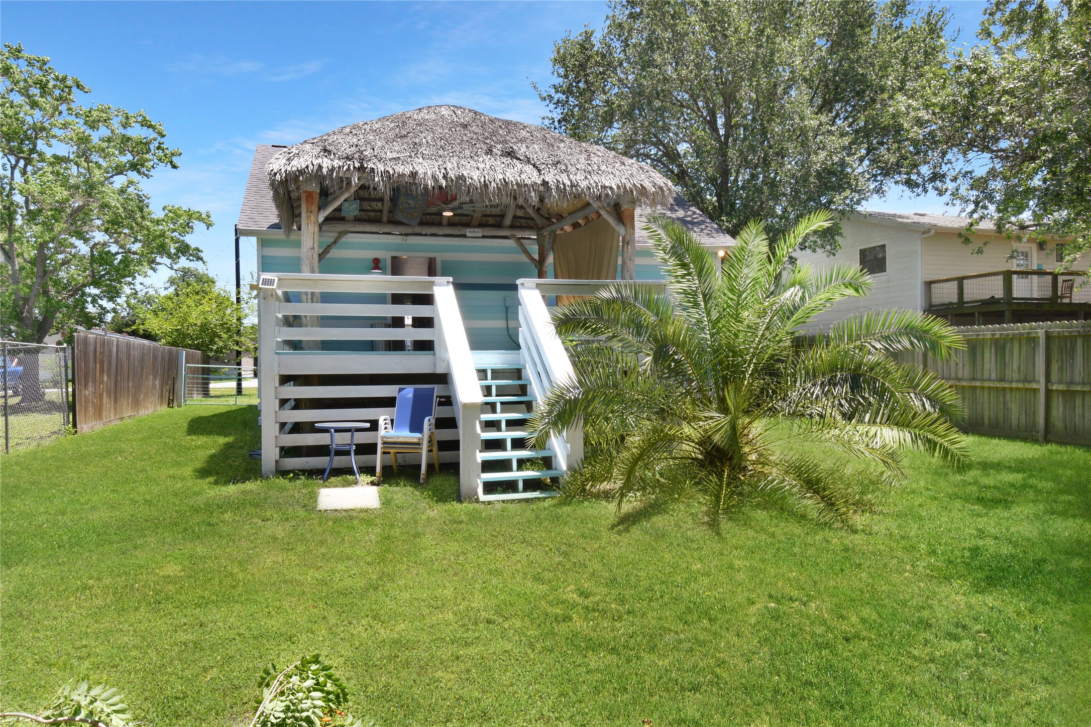 320 10th Street Dickinson, TX 77539 - Photo 4 of 21 Discover your private oasis with a lush green yard and charming tiki-style hut, perfect for relaxation and entertaining in your own backyard paradise.