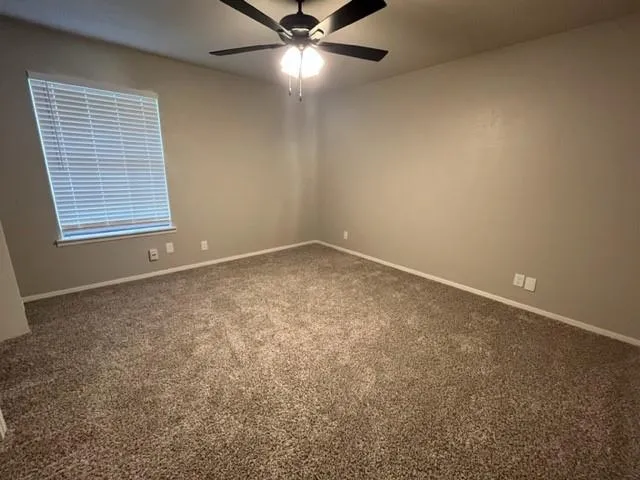 an empty room with a window and a fan