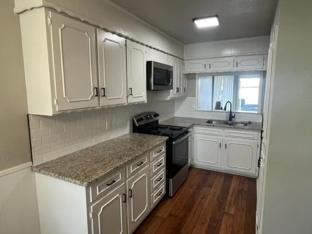 a kitchen with stainless steel appliances granite countertop a stove a sink and a microwave