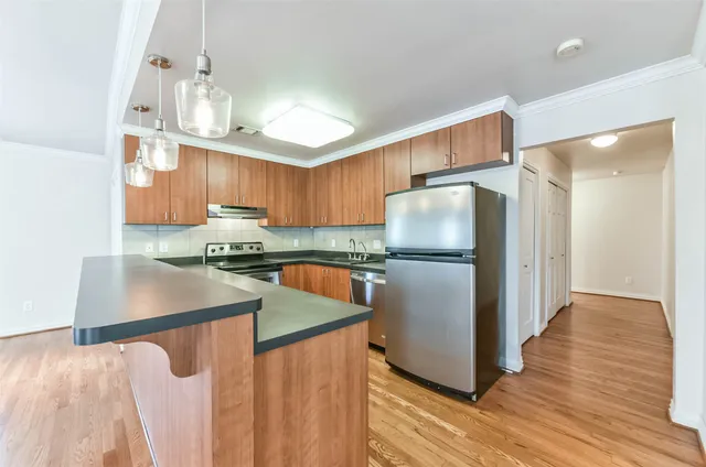 a kitchen with stainless steel appliances granite countertop a refrigerator a sink dishwasher a stove with wooden floor and cabinets