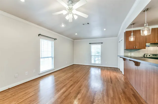 a view of an empty room with window and wooden floor