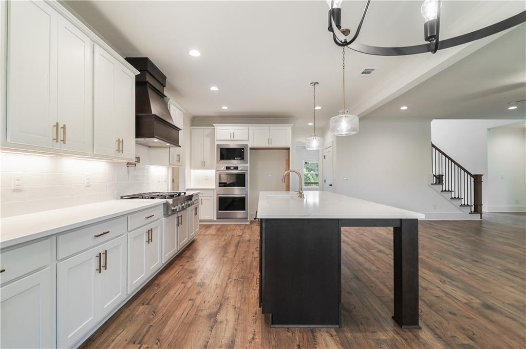 2113 Stonegate Way Monroe, GA 30656 - Photo 25 of 43 a kitchen with stainless steel appliances kitchen island granite countertop a table chairs in it and wooden floors