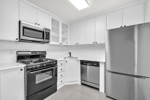 a kitchen with stainless steel appliances white cabinets and a stove a refrigerator with wooden floors