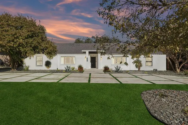 a view of a white house with a yard and plants