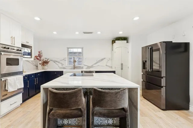 a kitchen with a sink a stove a refrigerator and white cabinets