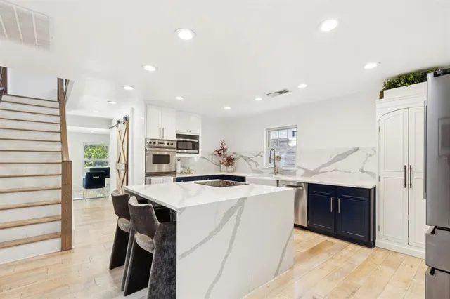 a kitchen with stainless steel appliances granite countertop a sink a stove and a wooden floors