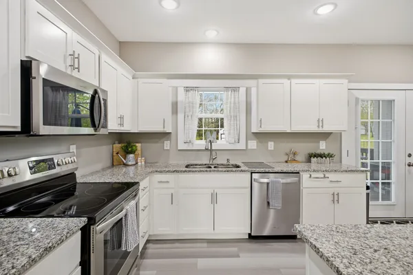 a kitchen with stainless steel appliances granite countertop a sink stove microwave and refrigerator