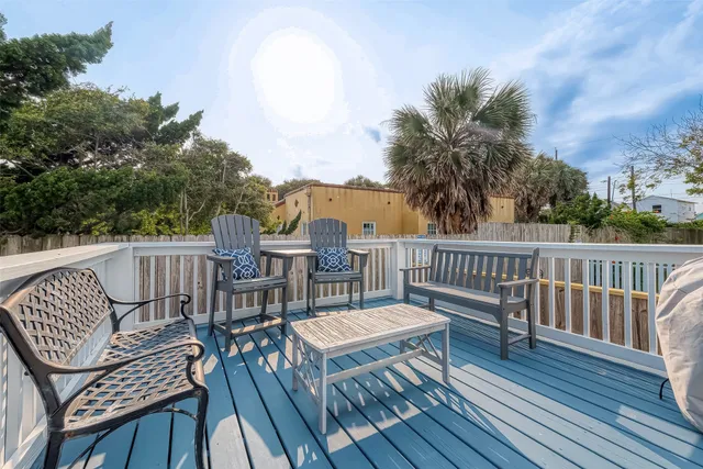 a view of a balcony with wooden floor chairs and wooden fence