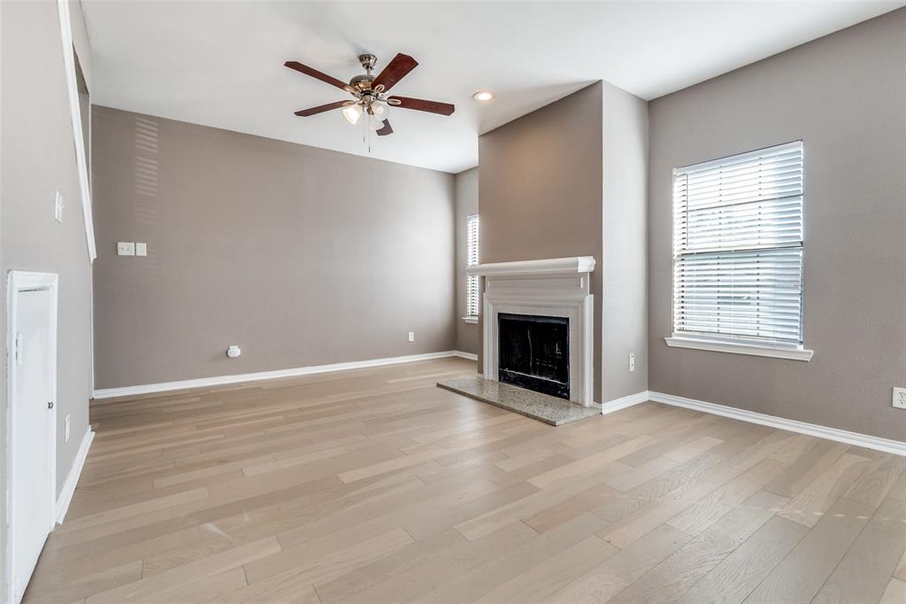 8750 Park Lane, Unit 147 Dallas, TX 75231 - Photo 12 of 20 Unfurnished living room featuring a ceiling fan, plenty of natural light, light wood-style flooring, a fireplace with raised hearth, and recessed lighting