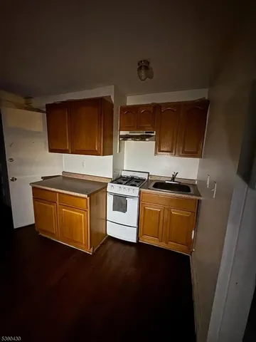 a kitchen with granite countertop a stove and a wooden floor