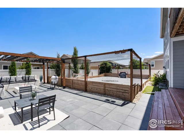 a view of a patio with couches table and chairs with wooden floor and fence